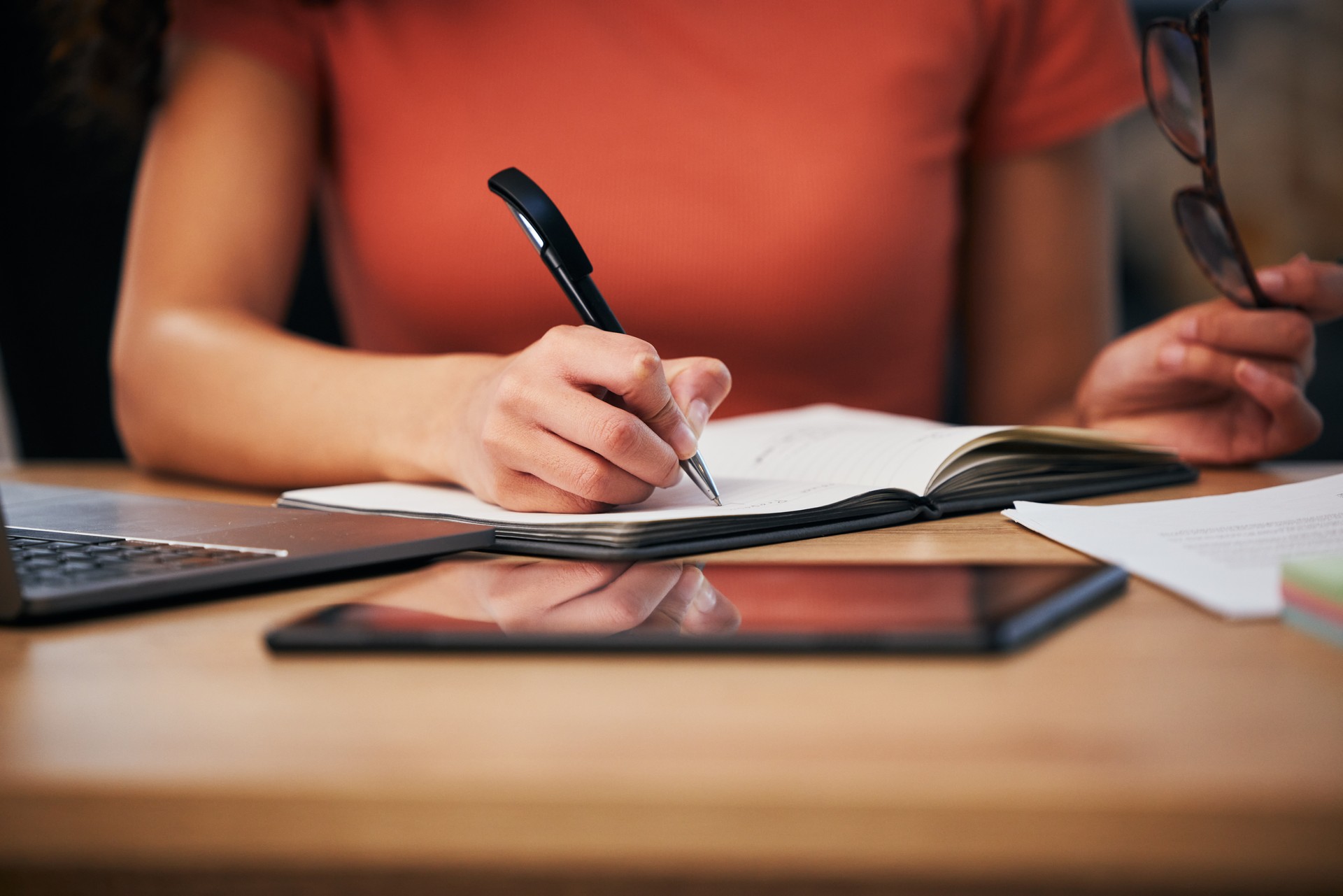 Notebook, office and hands of person writing summary notes, schedule or event planner working on appointment calendar. Project, closeup secretary and receptionist planning agenda, journal or report